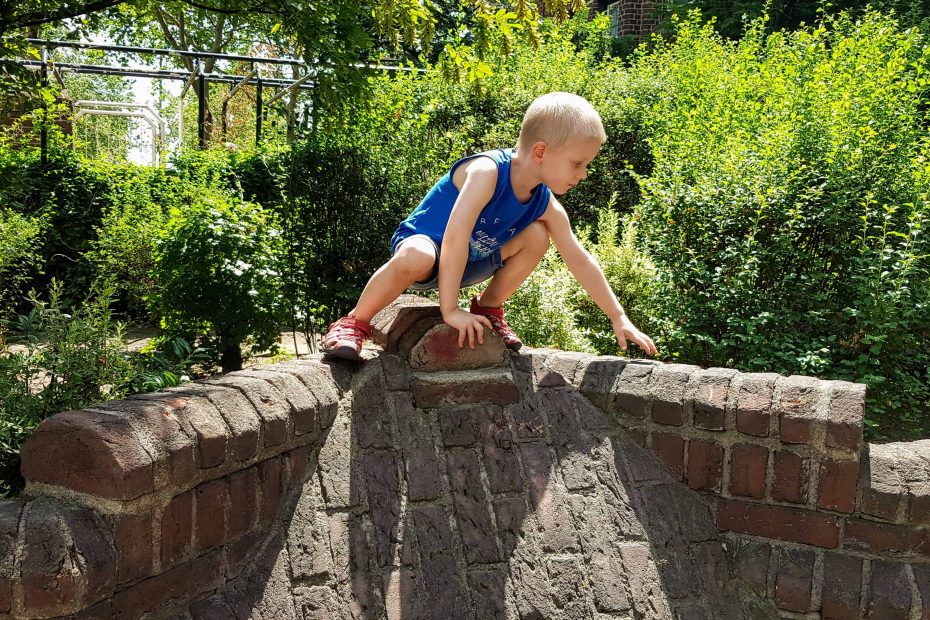 Kind klettert auf der Mauer